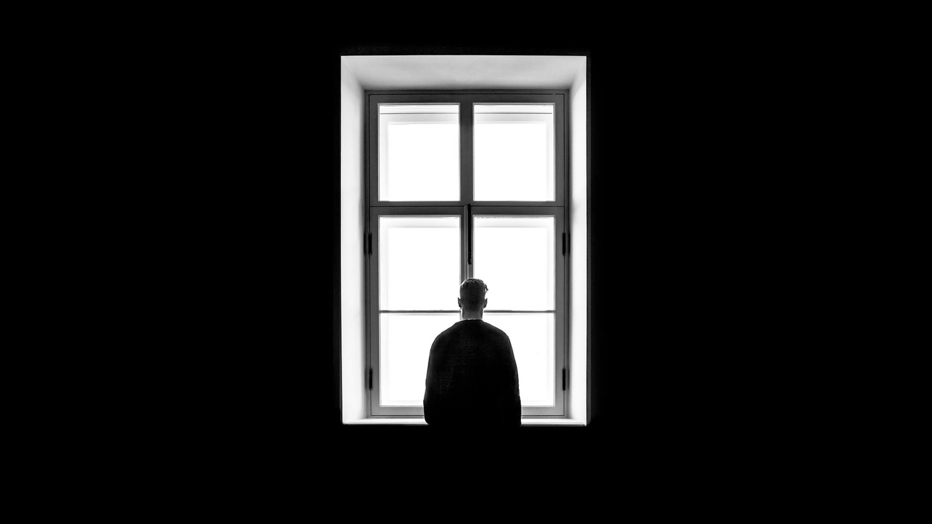 lonely man in black room with window